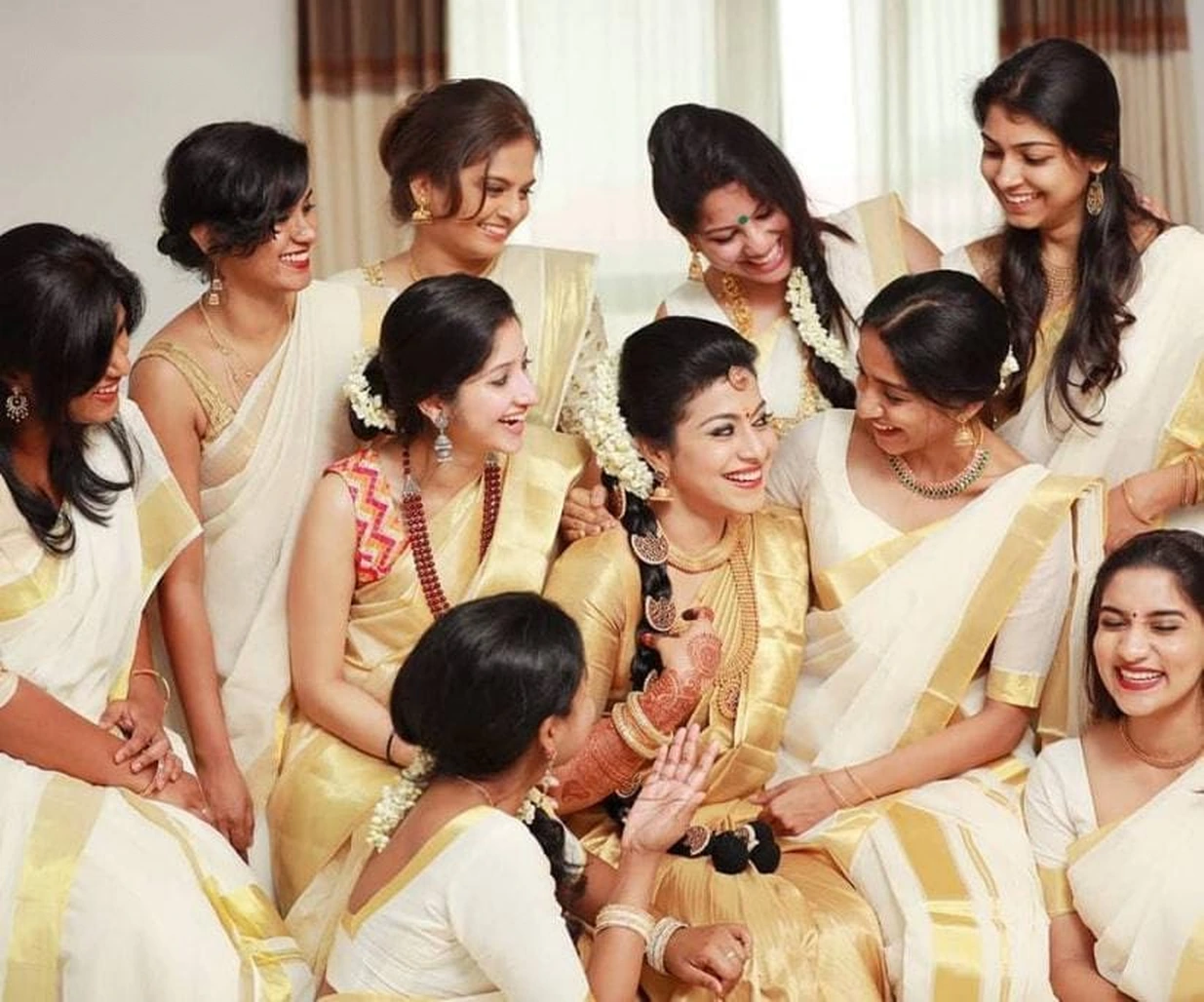 Women celebrating together in cream and gold traditional sarees